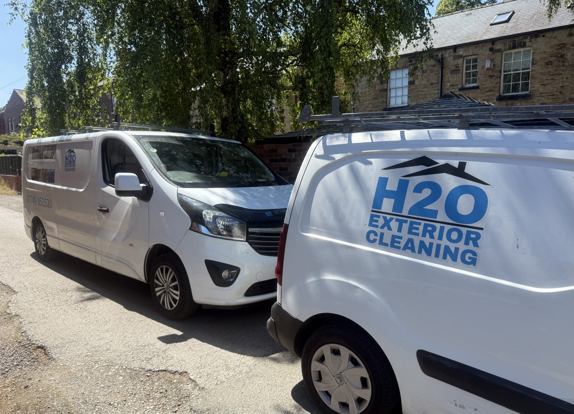 Two white service vans parked on gravel, with H2O exterior cleaning branding visible on the nearest vehicle